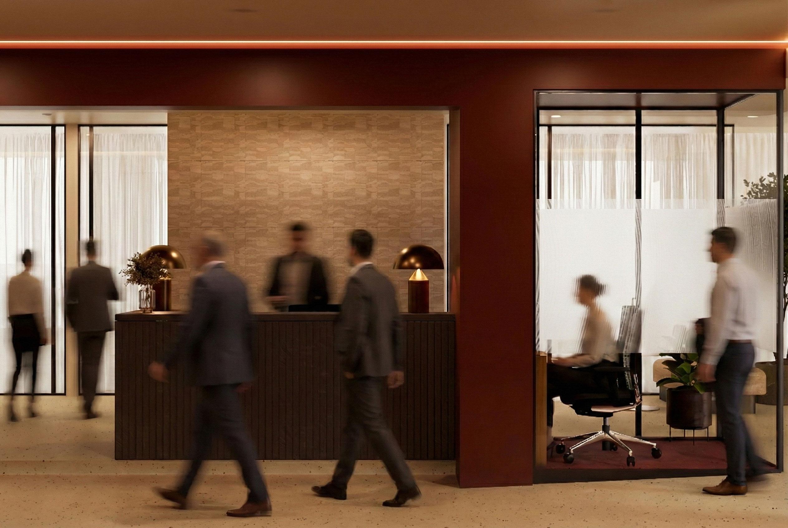 Reception aziendale progettata da Studio Archventil: parete in travertino, bancone in legno scuro a doghe verticali, lampade da tavolo dorate a cupola e pareti color terracotta, con ufficio privato vetrato sulla destra.
