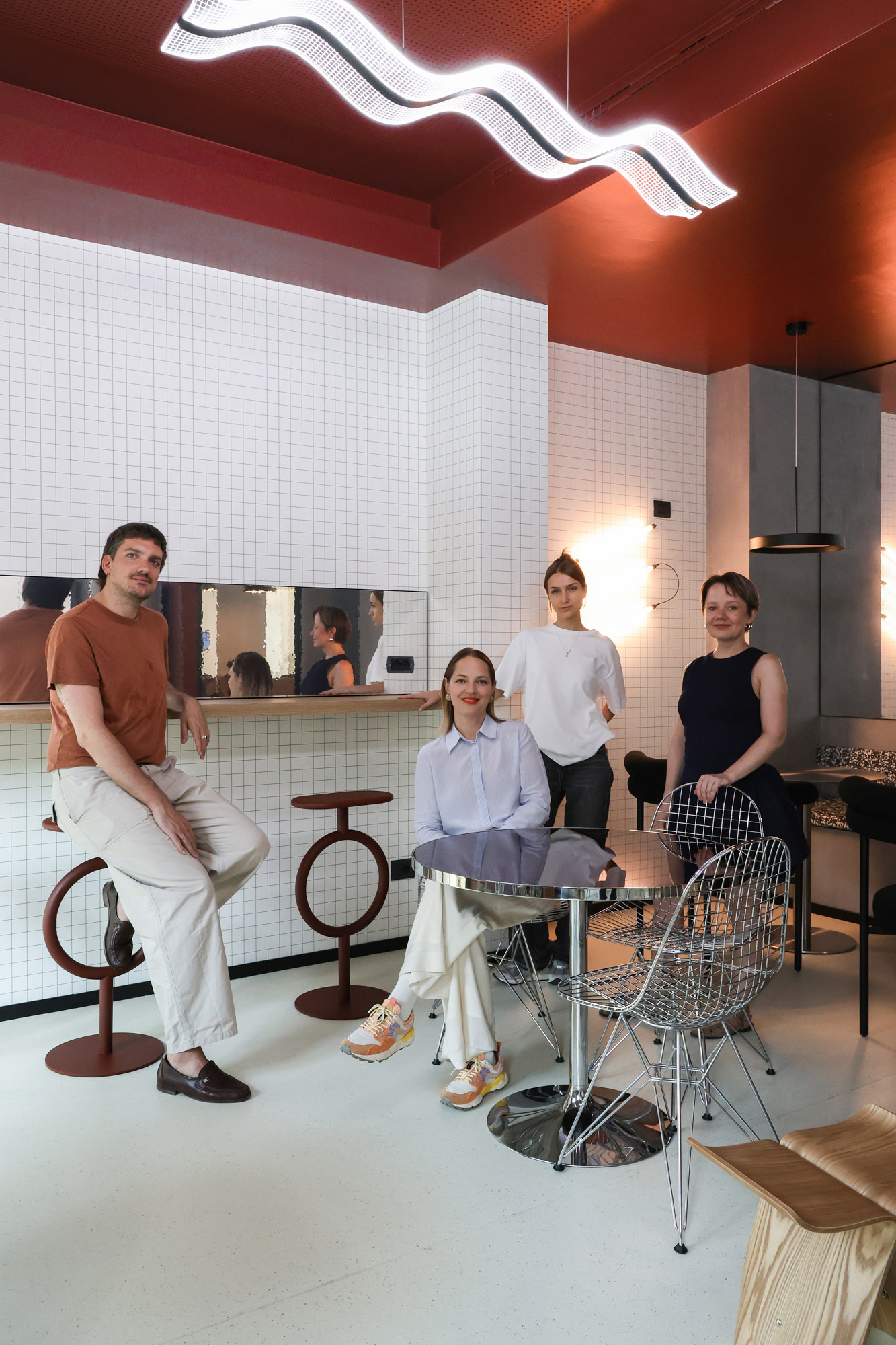 Il team di progetto al completo nella cucina di Pattari Headquarters a Milano, tra sgabelli Sancal, sedie Vitra e illuminazione dal segno grafico.